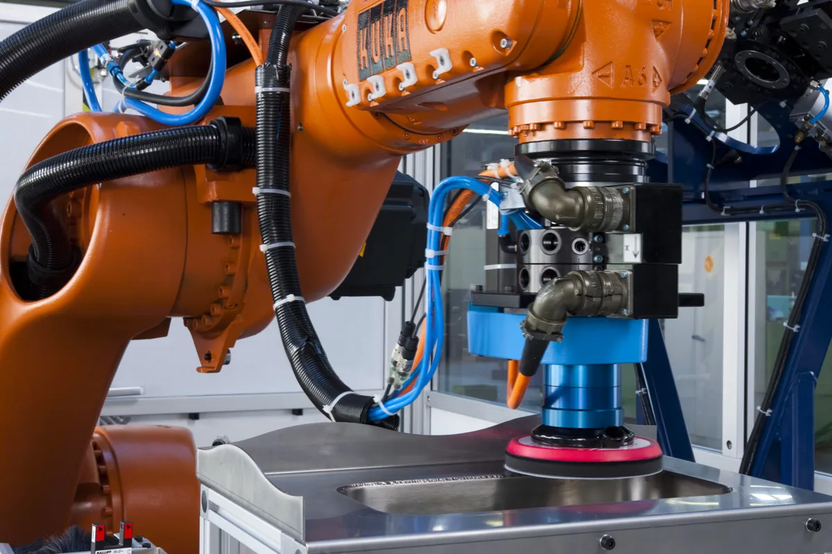 KUKA-robot schuurt met een schuurkop het oppervlak van een metalen onderdeel