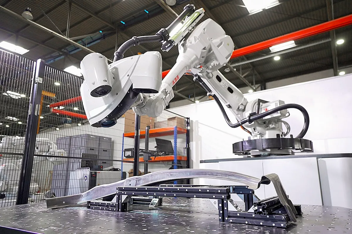 Robot met visiekop meet een gebogen aluminium onderdeel op een opspanning